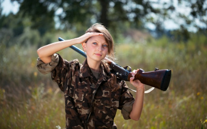 Young beautiful girl with a shotgun outdoor